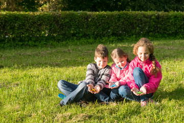 Naklejka na ściany i meble Three teenagers sitting enjoying on the grass playing in spinner