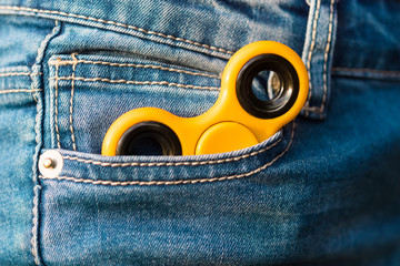 The yellow spinner lies in the jeans pocket