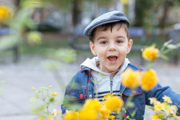 Young boy standing next to a blossoming bushes