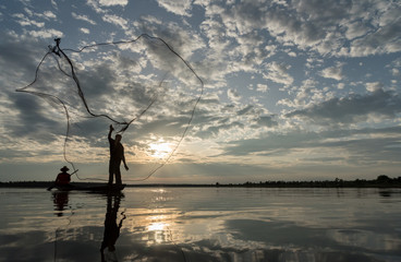 Silhouette of Fishermen throwing net fishing in sunset time at Wanon Niwat district Sakon Nakhon Northeast Thailand.