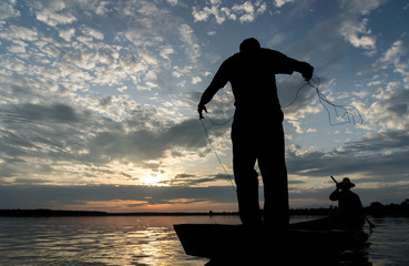 Silhouette of Fishermen throwing net fishing in sunset time at Wanon Niwat district Sakon Nakhon Northeast Thailand.
