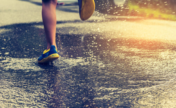  boy running on wet street .