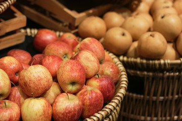 Apples in the basket lay beside Chinese pear in supermarket.
