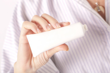 Woman's showing white cream tube 
