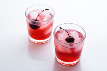 Drink with a cherry in a glass with ice on a white background. © ytochka89