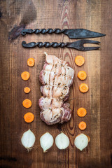 Raw roast pork preparation on rustic wooden background with cooking strings and kitchen tools, top view, flat lay