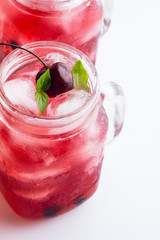 Glass mug with red drink, berries and ice on a white background. © ytochka89