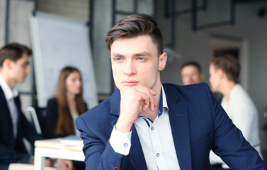 Businessman with colleagues in the background in office.