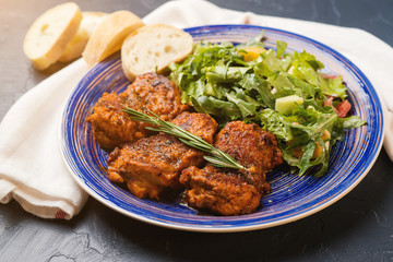 Platter of chicken thighs piri piri coated in hot sauce with salad.