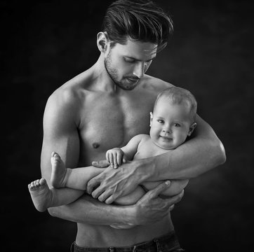 Black&white portrait of a glad father carrying his cute son
