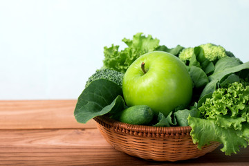 close up green apple with mixed green vegetable  in  basket and wooden fork and spoon for healthy organic green food concept