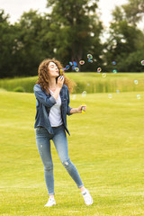 The happy woman blowing bubbles in the park