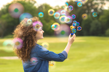 The attractive woman blowing bubbles in the park