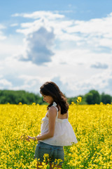 Fototapeta premium Young hipster girl enjoying summer in the yellow filed background, vertical orientation