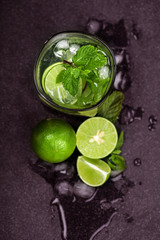 Close up top view or overhead shot of  the fresh mojito cocktail with fresh lime and mint leaf on black stone background