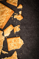 Top view of the whole wheat crackers flat lay as border on black stone of frame for baked food...