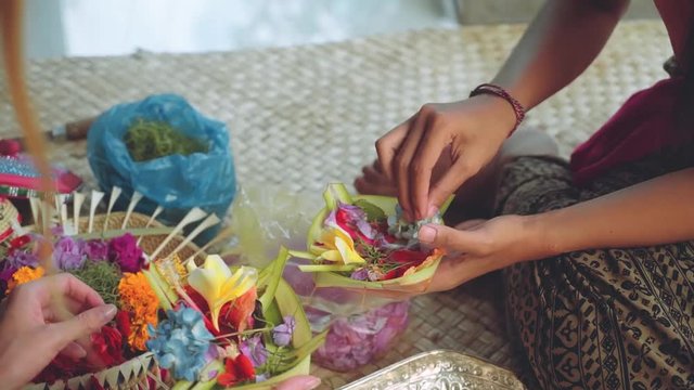 Two girls making balinese offerings Canang sari, slide