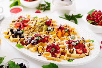 Variety of Belgian wafers with berries, chocolate and syrup. 