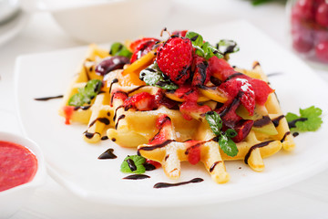 Variety of Belgian wafers with berries, chocolate and syrup. 