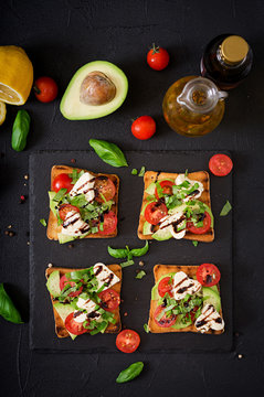 Sandwich toasts with tomatoes, mozzarella, avocado and basil with balsamic vinegar. Flat lay. Top view