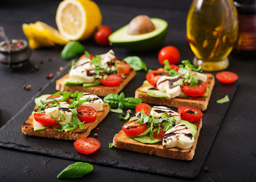 Sandwich toasts with tomatoes, mozzarella, avocado and basil with balsamic vinegar.