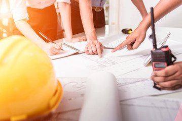 Engineer worker man discussing about building plan for construction at job site, working on desk.