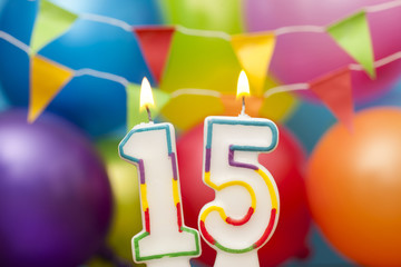 Happy Birthday number 15 celebration candle with colorful balloons and bunting