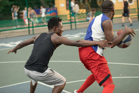 African american man friends playing on basketball court. Real authentic activity.