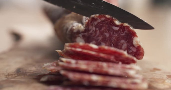 slow motion of female teen hand slicing dried italian salami