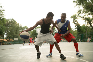 Fototapeta na wymiar African american man friends playing on basketball court. Real authentic activity.