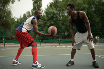 Fototapeta premium African american man friends playing on basketball court. Real authentic activity.