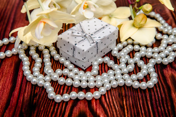 Gift box on a background of yellow orchids and pearls 