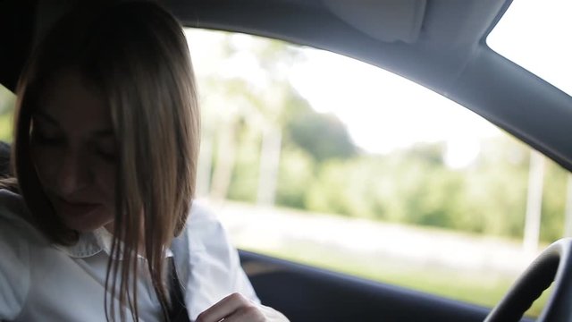 Young businesswoman sitting into the car, speaking on the phone and flirting