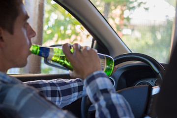 young man drinking beer while driving. the problem of alcoholism and drunk driving.