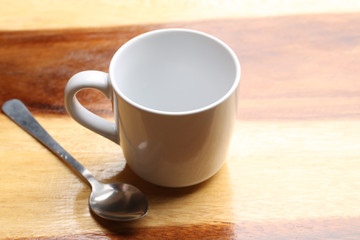 white cup and spoon on wood floor