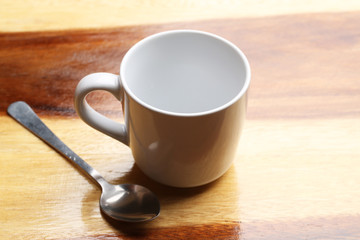 white cup and spoon on wood floor