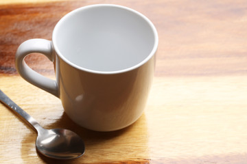 white cup and spoon on wood floor
