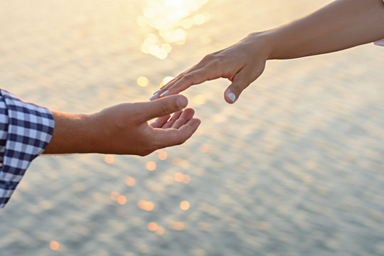 A lover boy makes an offer to his deushke on the beach at sunrise (dawn). Creating a family. Creating a family. hands of the bride and groom on the background of the sea close-up.