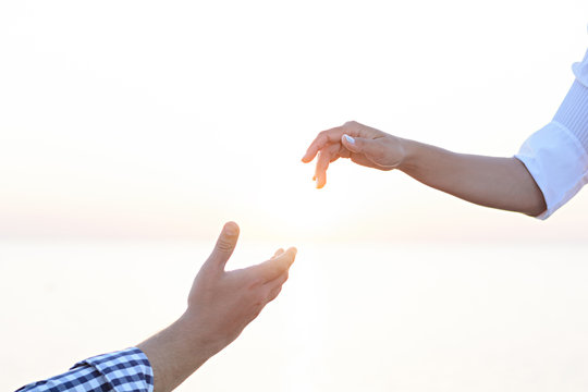A lover boy makes an offer to his deushke on the beach at sunrise (dawn). Creating a family. Creating a family. hands of the bride and groom on the background of the sea close-up.