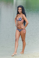 Obraz premium Young beautiful black-haired woman posing on the beach in the water