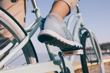 Female foot in a blue sneaker and a bicycle on the beach