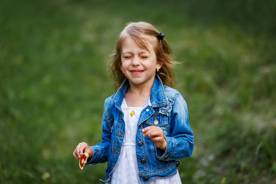 Cute smiling girl with a dasy in her hair. Beautiful girl with outside in summer with closed eyes making a wish