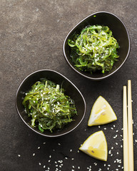 Salad Chukka from seaweed healthy food in dark ceramic bowls on a dark background with lemon slices...