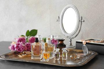 Metal tray with bottles of perfume on table