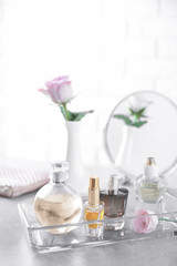 Obraz na płótnie Canvas Glass tray with bottles of perfume on table