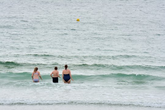 Une mère et ses deux enfants vont prendre un bain de mer sur une plage en Bretagne