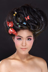 Creative Hair style with colorful butterfly on Black hair, korea  girl smiling with teeth, open shoulders, pink eyeshadow, studio lighting with black background, copy space for text and logo