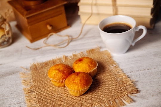 Muffins and coffee on a wooden table.