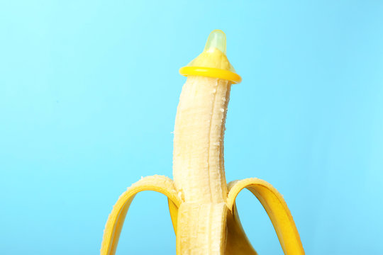 Condom on banana against color background. Safe sex concept