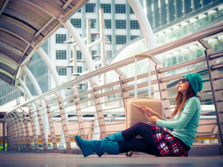 Asian woman traveler sitdown on the floor in airport,  relexing with her tablet and look around.